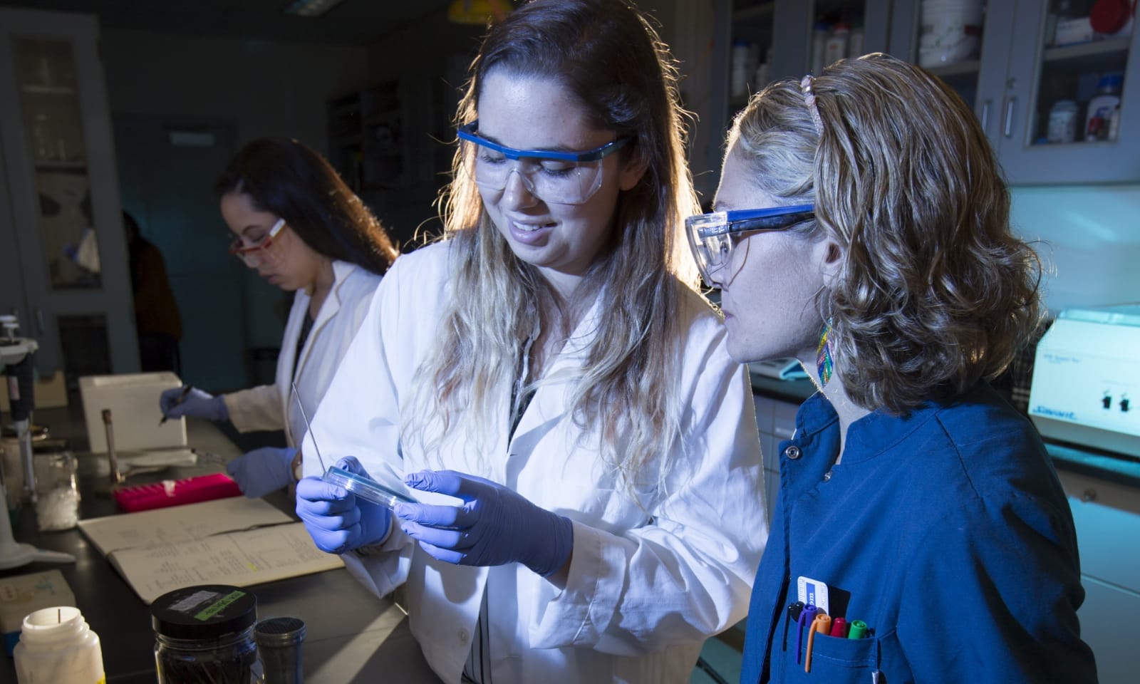 A student and a professor examine a sample in a lab.